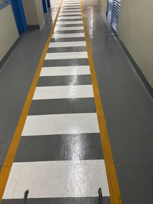Demarcación de senda peatonal pintada en piso industrial